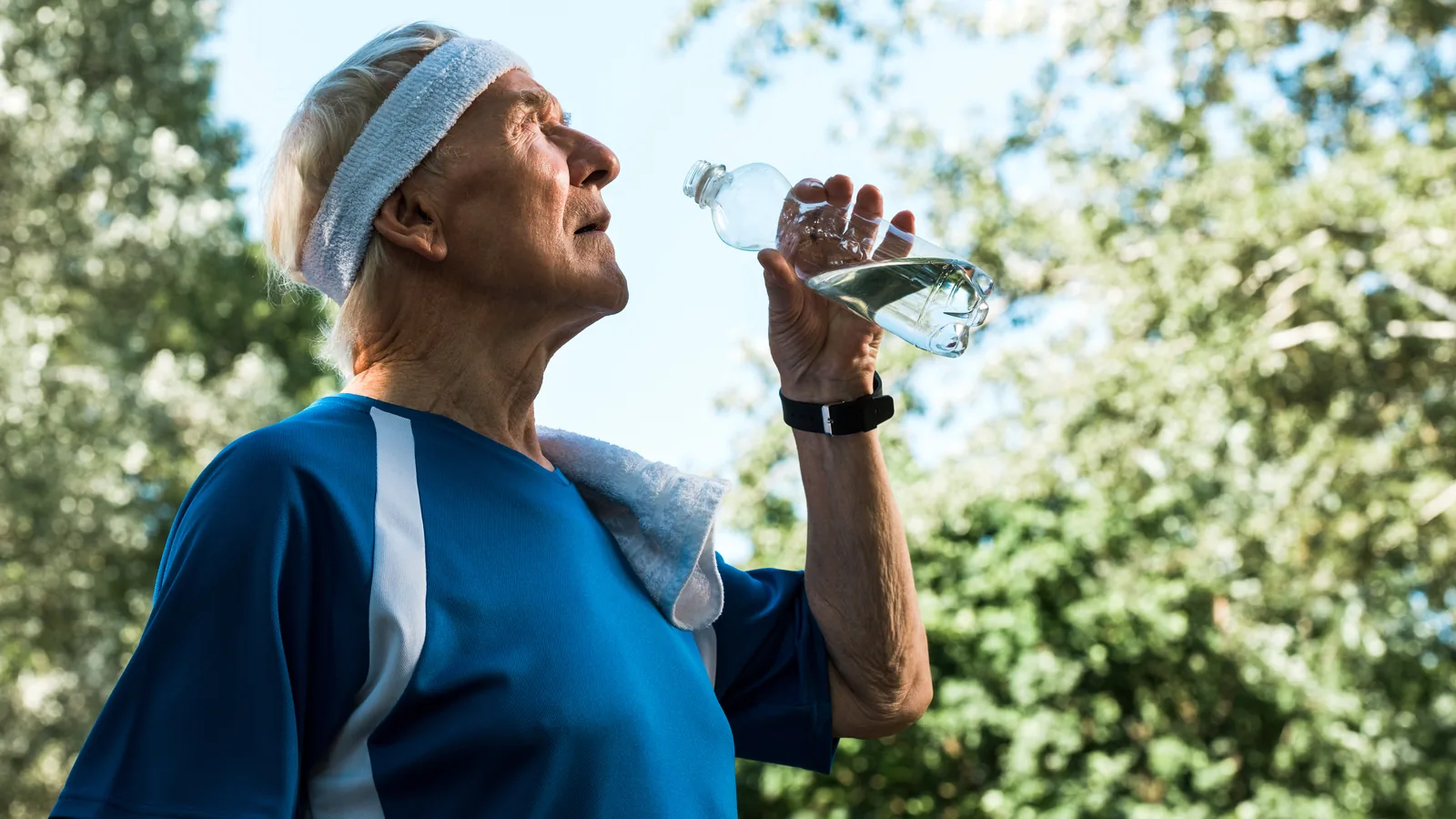 Glass of water next to an older person at home in the summer.